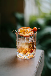 Composition of cold icy whiskey garnished with lemon slice and placed on concrete table