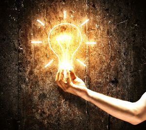Person holding illuminated light in dark room