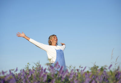 Low angle view of woman standing on field against clear sky