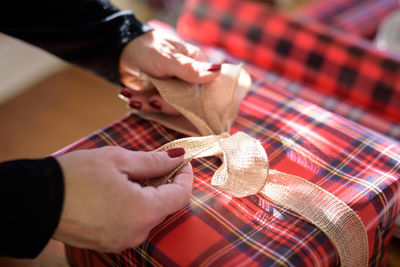 Cropped hands of woman wrapping gift at home