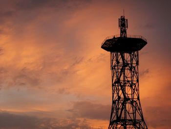 Low angle view of electricity pylon against sky during sunset