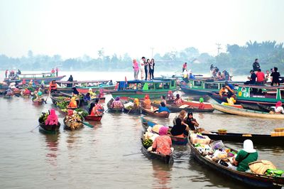 People on boat in river against sky