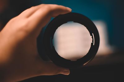 Close-up of person holding camera against sky