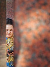 Woman looking away while standing against blurred background