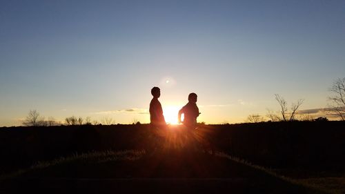 Silhouette people standing on landscape against clear sky during sunset