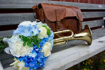 Close-up of wedding flowers a bag and a trumpet on bench
