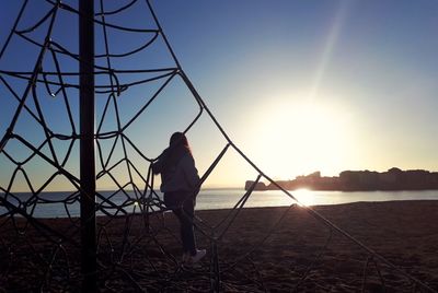 Rear view of man standing on land against sky during sunset