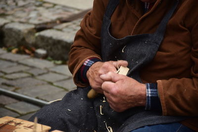 Midsection of man holding hands sitting outdoors