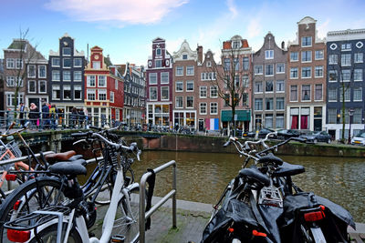 Bicycles at a canal against buildings in amsterdam the netherlands