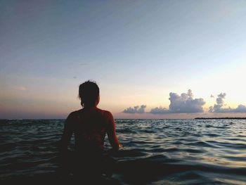 Man on sea against sky during sunset