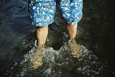 Low section of man standing in water