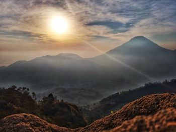 Sunrise view of mountains against sky, rock and trees