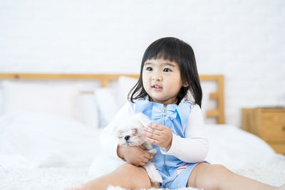 Cute girl with dog on bed at home