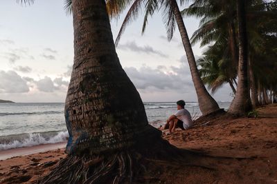 People sitting on beach by sea against sky