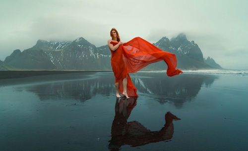 Redhead model in red dress on reynisfjara beach scenic photography