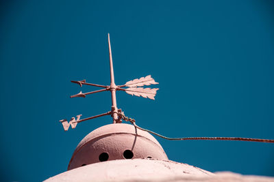 Low angle view of old weather vane against clear blue sky