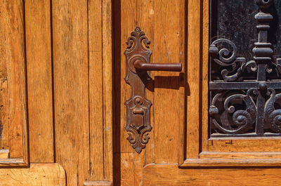 Part of a vintage door. wooden double door with wrought iron pattern and antique lock with handle.