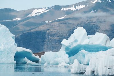 Icebergs in sea against mountain