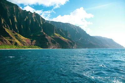 Scenic view of sea by mountains against sky