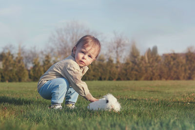 Cute baby boy and white fluffy bunny in the garden 