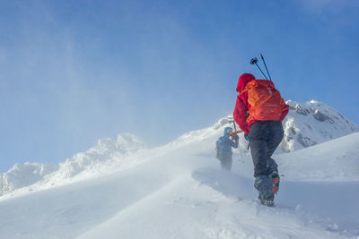 Low angle view of hikers on snow covered mountain against sky