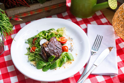 Beef steak chateaubriand with corn salad and arugula leaves, cherry tomato slices, olive oil