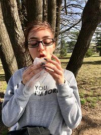 Young woman smoking while sitting on tree trunk