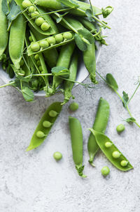 Fresh green peas pods and green peas with sprouts on concrete background. 