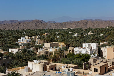 High angle view of buildings and palm trees with mountains against sky