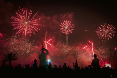 Silhouette people against firework at night