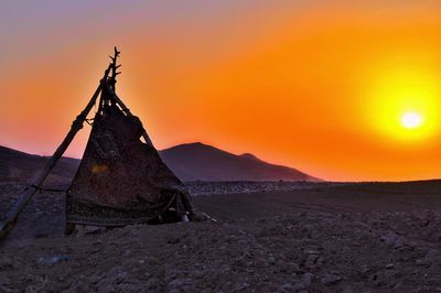 Traditional windmill on land against sky during sunset