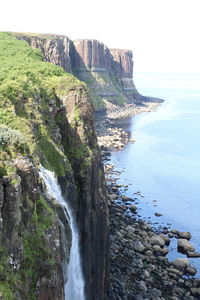 Scenic view of sea by cliff against sky