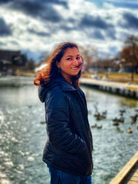 Portrait of smiling woman standing against lake