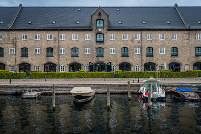 Boats moored in canal against building