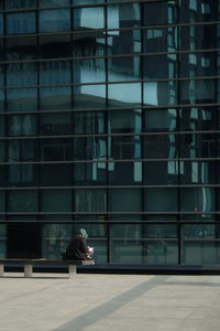 Low angle view of woman sitting in front of building