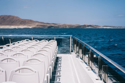 Chairs by sea against blue sky