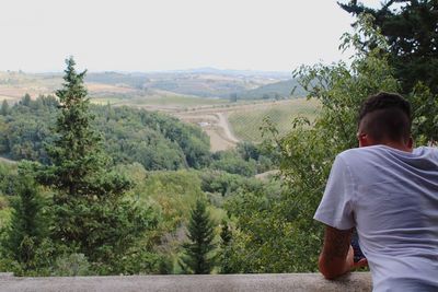 Rear view of man looking at landscape against sky