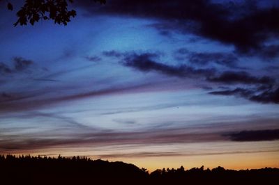 Low angle view of silhouette trees against dramatic sky