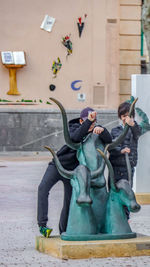 Friends playing by statues in city