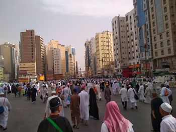 People on street amidst buildings in city against sky