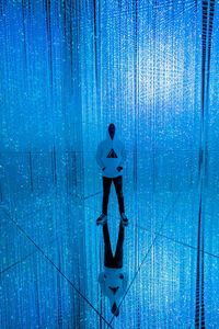 Digital composite image of silhouette man standing against blue wall