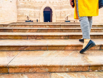 Low section of woman walking on staircase at temple