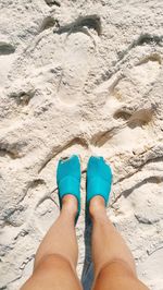 Low section of woman standing on sand