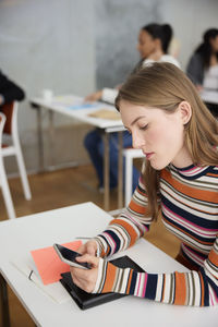 Young woman using cell phone at workshop