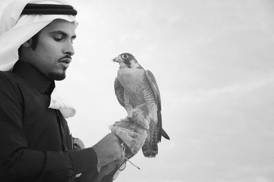 Man with eagle against sky