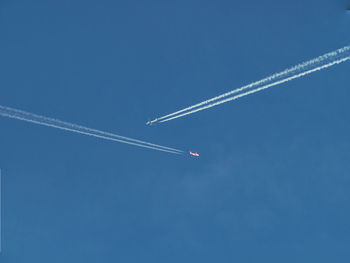 Low angle view of airplane flying against clear blue sky