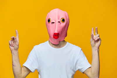 Rear view of woman wearing mask against yellow background