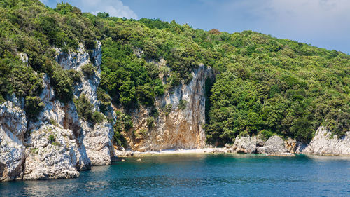 Scenic view of rocks by sea against sky