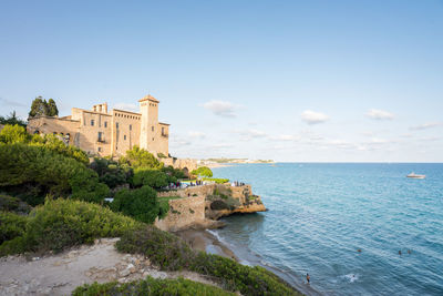 Buildings by sea against sky