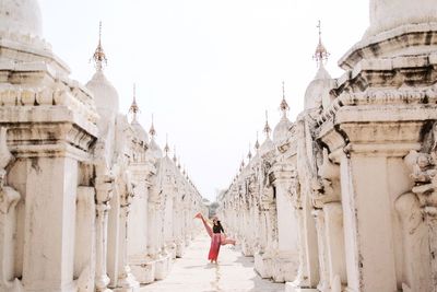 Woman standing outside temple against clear sky